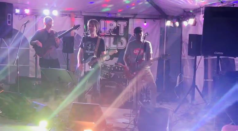 Dirt Child performing under colorful stage lights inside a tent at FLX Public House, in front of the Dirt Child banner